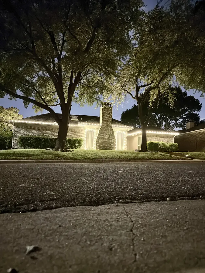 Home at dusk with warm-white lights tracing the roofline